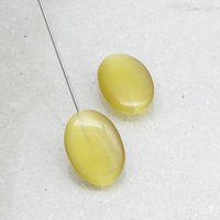 Half-drilled oval fiber optic glass pendant beads have a cat's eye effect when seen from different angles. Beads measure approximately 18mm long, 13mm wide, and 5-7mm thick.