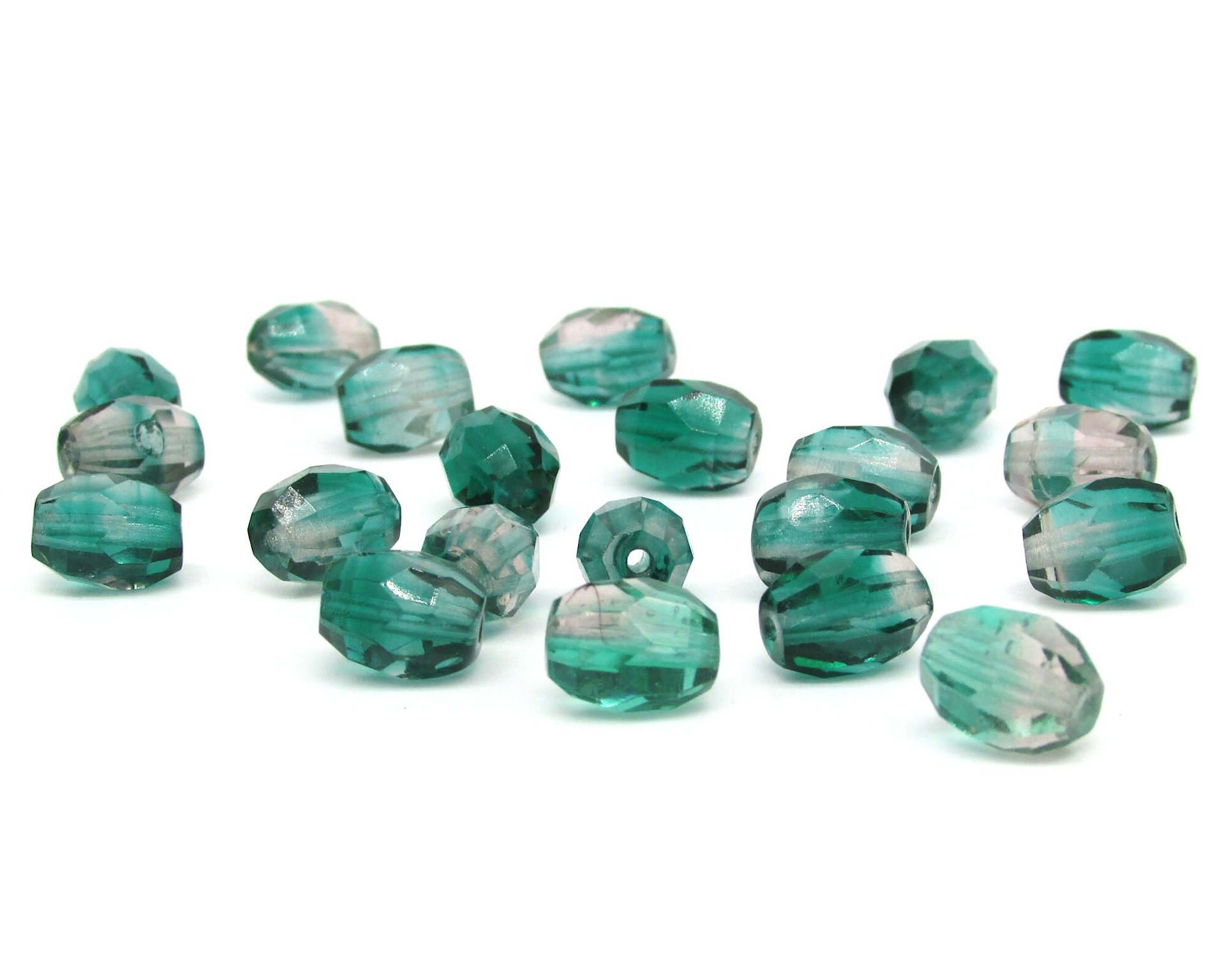 Faceted two-tone oval barrel beads measure 10mm long by 8mm wide, with 1mm center-drilled lengthwise holes. Fire polished Czech glass beads are a combination of translucent emerald green and light amethyst purple.
