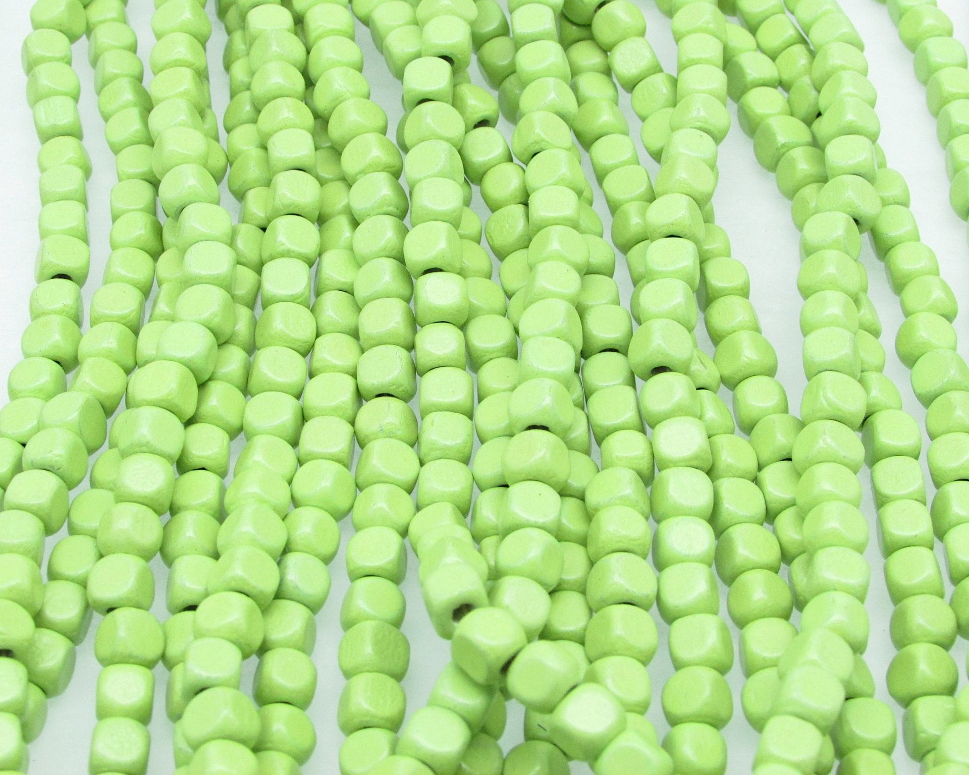21 inch strand of vintage wooden beads has approximately 100 light green 5mm rounded cubes. 