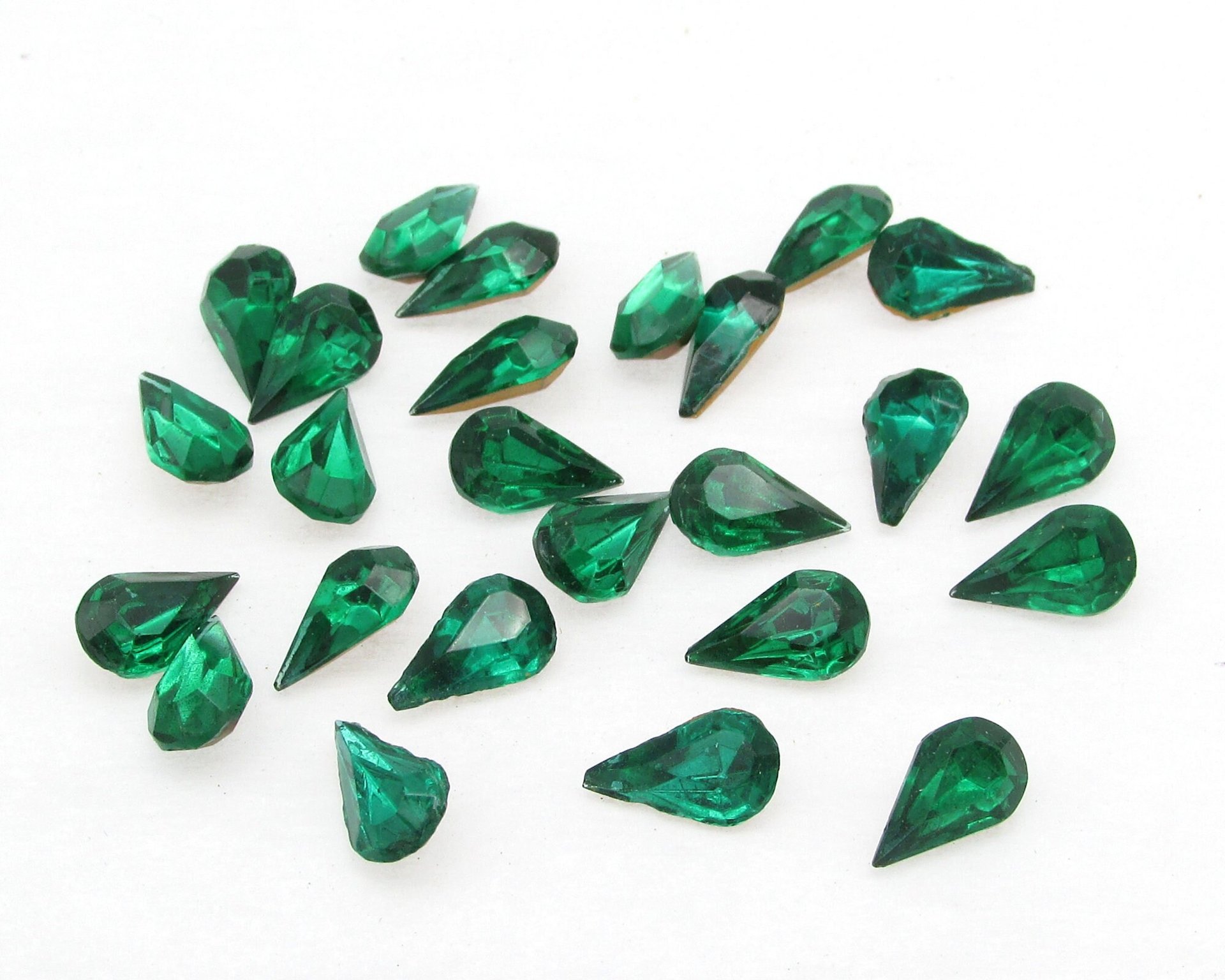 Vintage tin table cut pear shape rhinestones are translucent emerald green backed with gold foil. Point back stones measure 10mm long and 6mm wide.