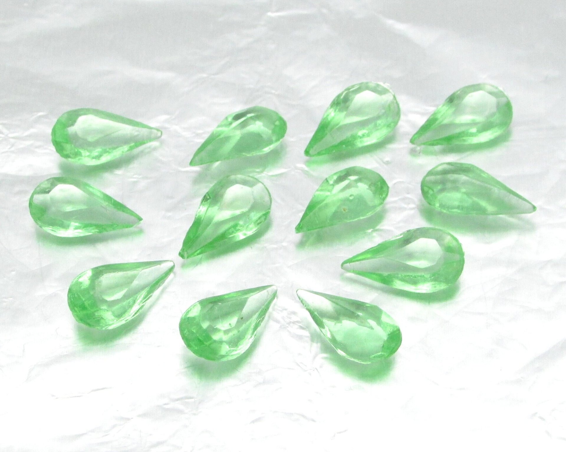 Vintage tin table cut pear shape rhinestones are translucent pastel green. Unfoiled point back stones measure 14mm long and 8mm wide.