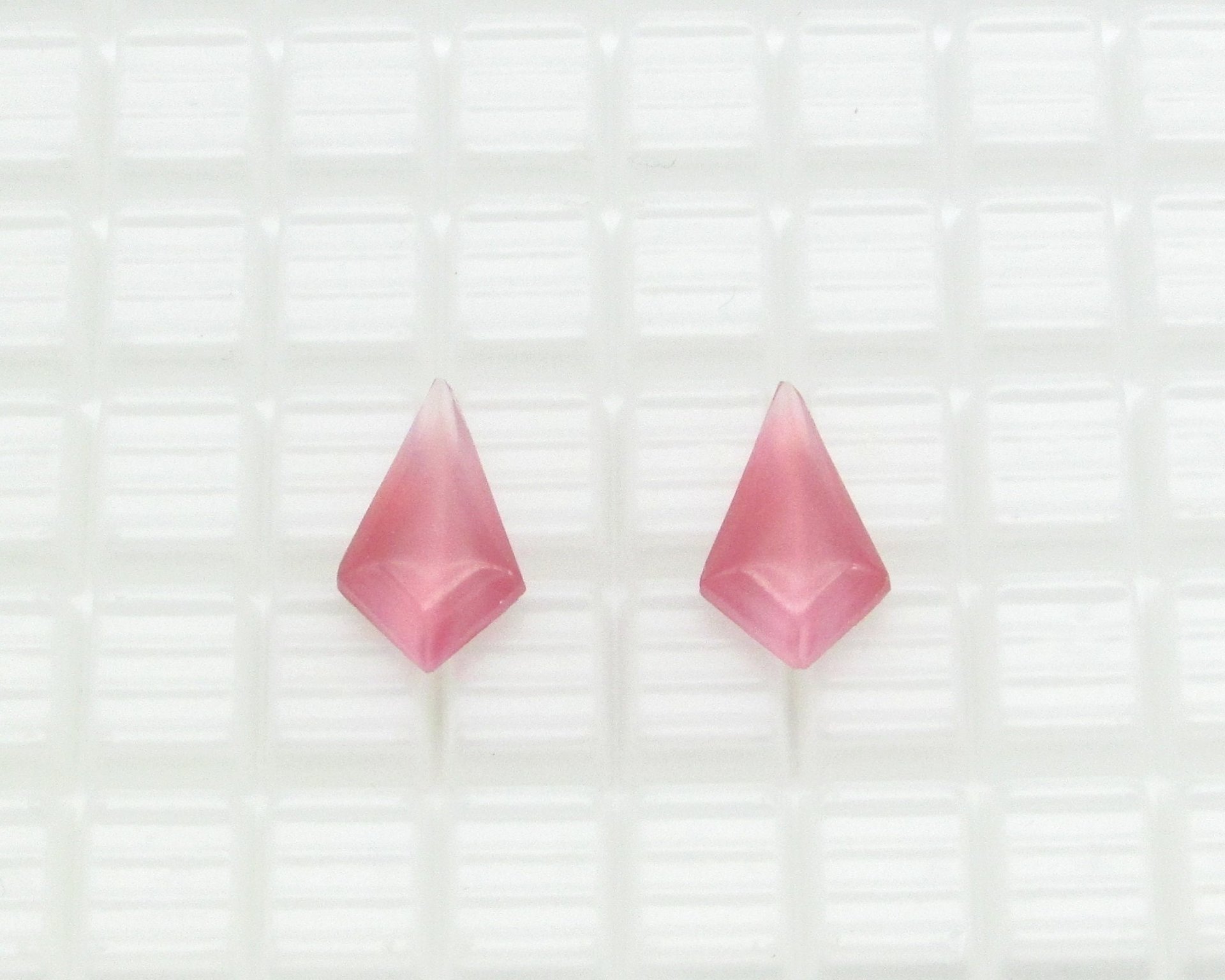 Opaque glass rhinestones are kite shaped with a smooth, rounded tops and faceted backs. Stones measure 19mm long, 11mm wide, and 5.5mm thick at the center. Pointed backs are unfoiled. Choose from either rose pink or light blue. 