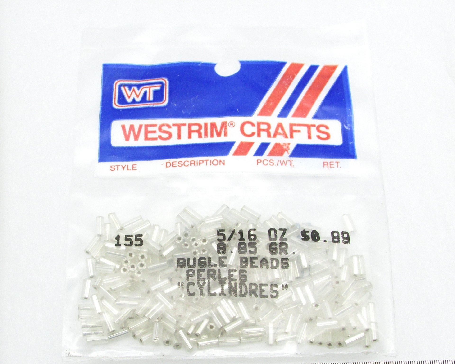Vintage silver foiled bugle beads are still sealed in their original packaging. Tiny cylinders measure 5mm long by 2mm wide.