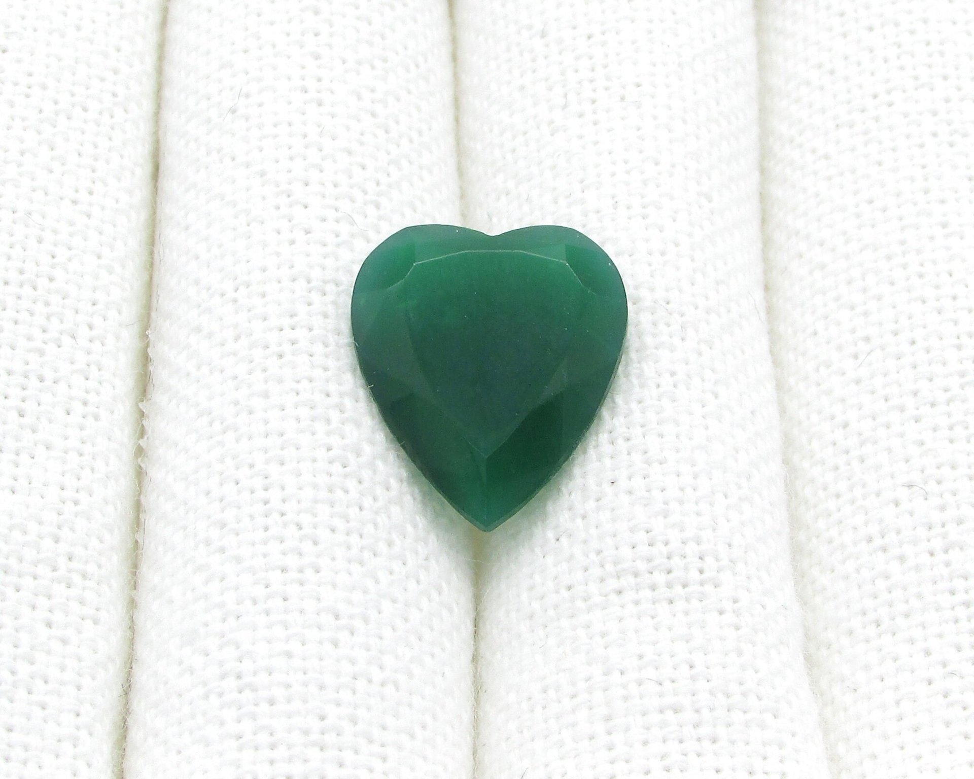Semi-translucent jade green faceted glass heart measures 19mm long and 16mm wide.  Facets meet in a point a the back of the stone.  The back of the stone is unfoiled. 