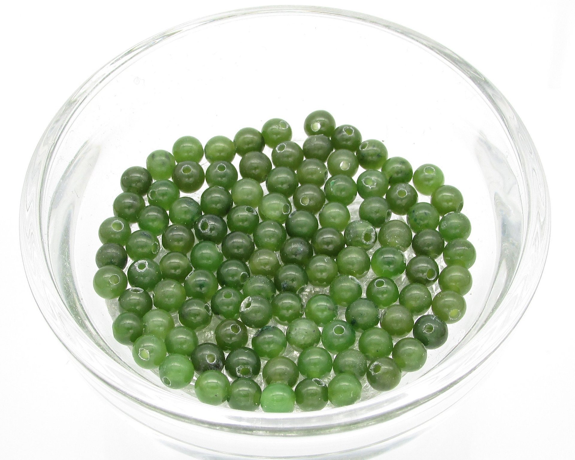 Nephrite jade round beads are deep olive green beads with center-drilled holes. Nephrite is a naturally occurring mineral; translucently, color, and inclusions vary from bead to bead. Available sizes: 4mm, 8mm and 10mm.