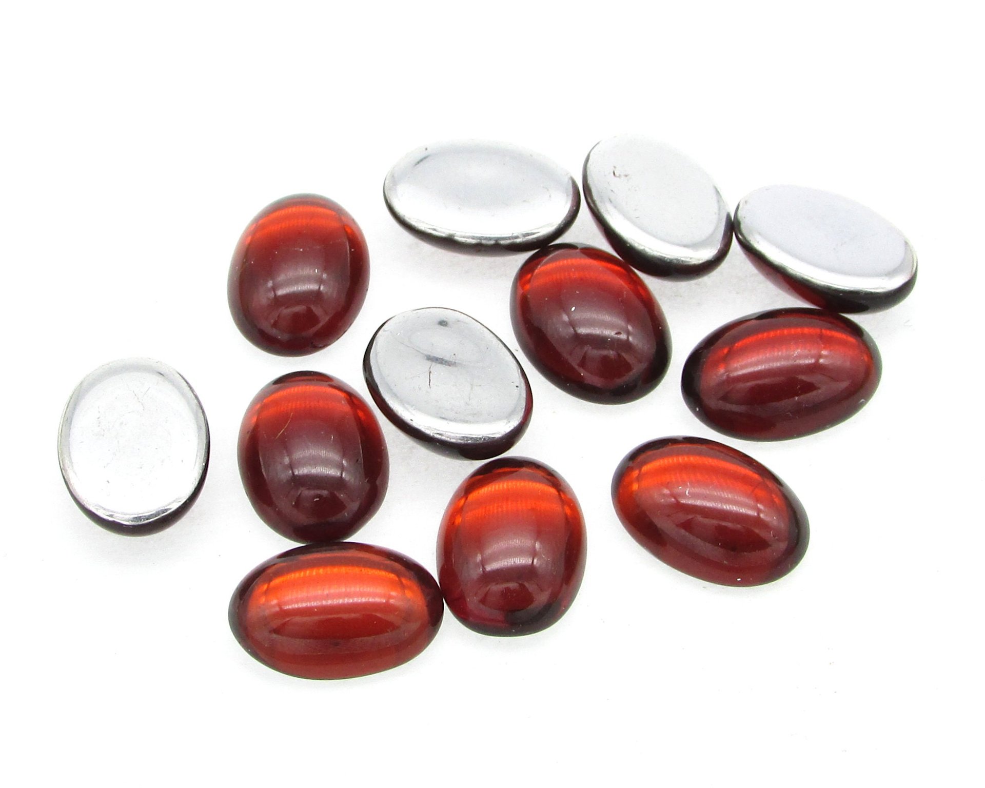Vintage glass cabochons are translucent ruby red with bright silver foil and the back. Oval stones measure 14mm long by 10mm wide, with a smooth 5mm dome.