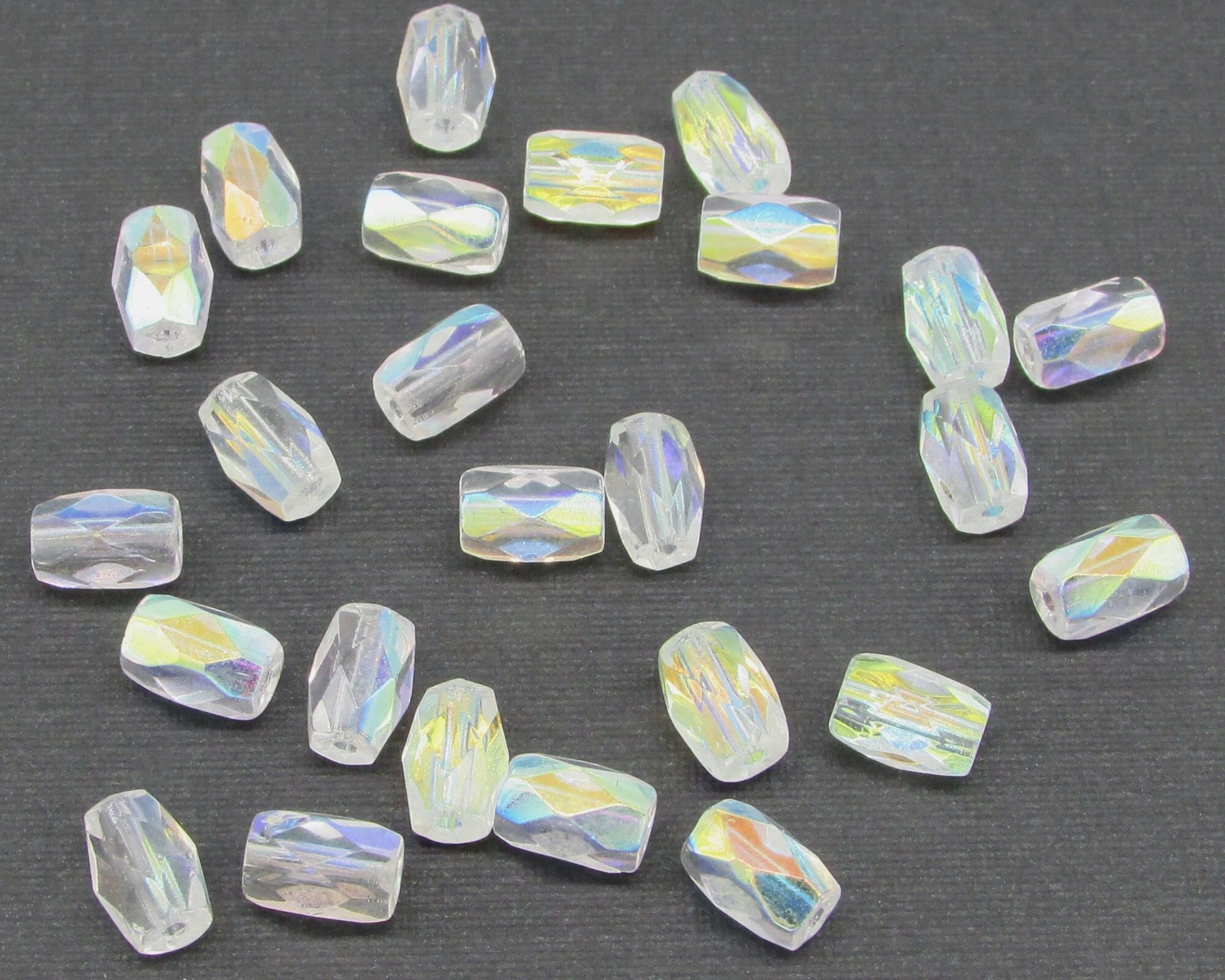 Small faceted barrel beads measure 7mm long by 5mm diameter, with a lengthwise 1mm hole. Clear fire polished glass beads have an iridescent coating.