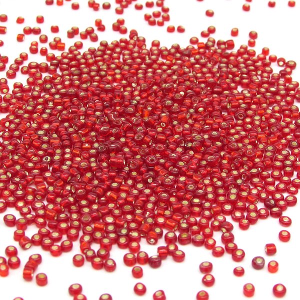 8/0 seed beads are translucent red mini rocailles with a gold foil lining. Beads average 2.5x3.5mm with round 1.0mm holes. There are approximately 38-40 beads per gram.